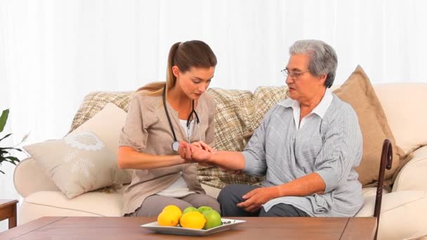 Beautiful nurse taking the pulse of her patient at home — Stock Video