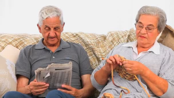 Frau strickt, während ihr Mann Zeitung liest — Stockvideo