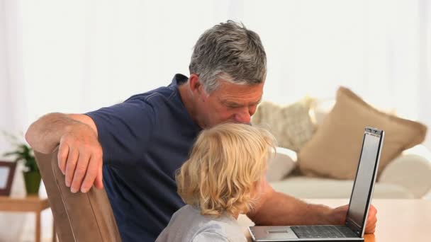 Дедушка с внуком смотрит на их ноутбук — стоковое видео