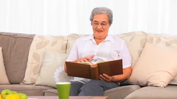 Vrouw kijken naar haar fotoalbum — Stockvideo