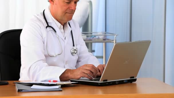 Starszy lekarz pracuje na swoim laptopie — Wideo stockowe