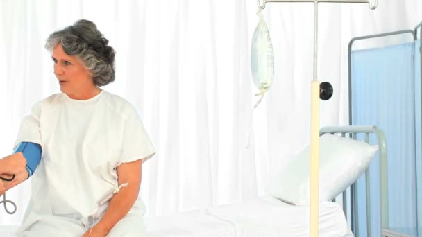 Strahlende Krankenschwester bei der Blutdruckmessung ihrer Patientin — Stockvideo