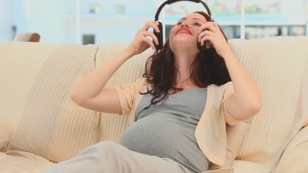 Nő, állítva, hogy a fejhallgató a hasában — Stock videók