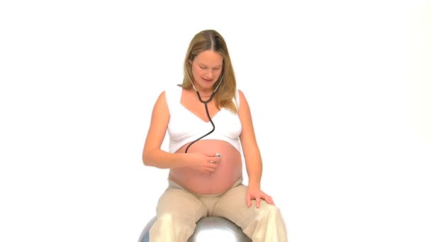 Pregnant woman listening to her belly with a stethoscope — Stock Video