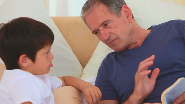 Een grootvader lezen van een boek met zijn kleinzoon — Stockvideo