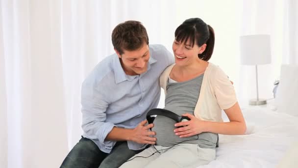 Pareja dejando que su futuro bebé escuche música — Vídeo de stock