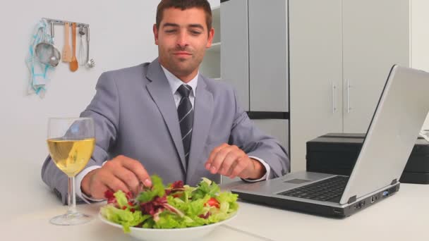 Бизнесмен работает над своим ноутбуком, пока он ест — стоковое видео