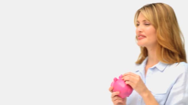 Cute blonde lady saving up her cash in a piggy bank — Stock Video