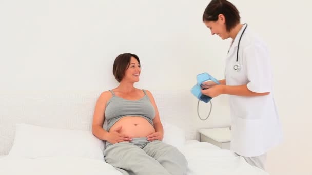 Nurse taking the blood pressure of her pregnant patient — Stock Video