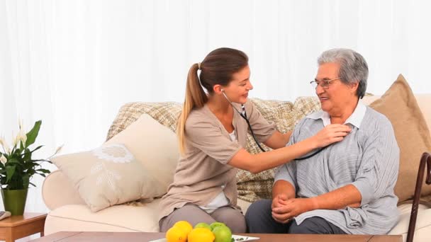 Lovely nurse taking the heartbeat of her senior patient — Stock Video