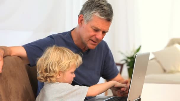 Мальчик с дедушкой смотрит в ноутбук — стоковое видео