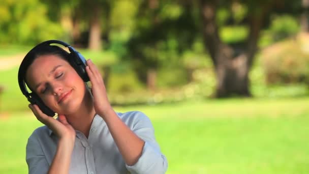 Νεαρή γυναίκα ακούγοντας μουσική σε εξωτερικούς χώρους — Αρχείο Βίντεο