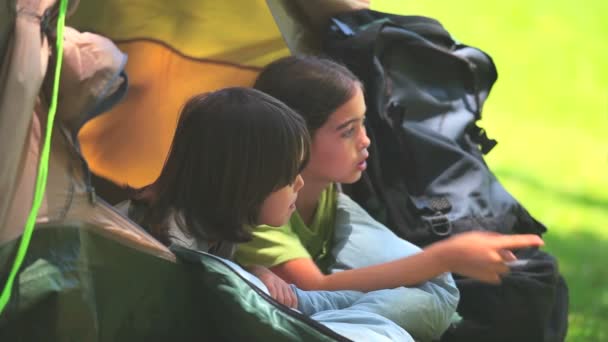 Crianças bonitas em uma tenda olhando para algo — Vídeo de Stock