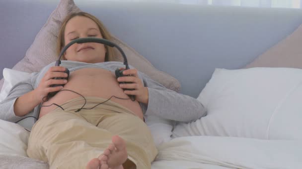 Mujer embarazada poniendo auriculares — Vídeo de stock