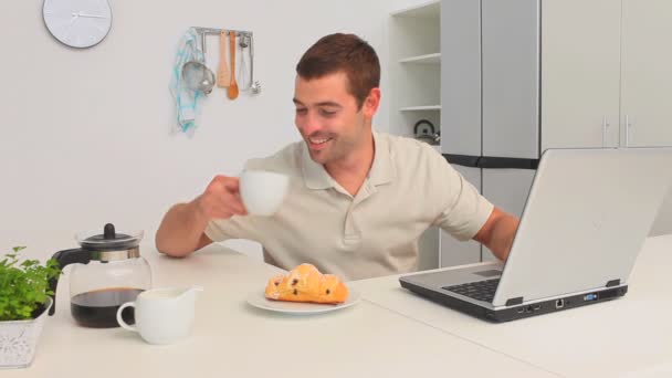 Человек пьет чашку кофе, пока работает над ноутбуком — стоковое видео