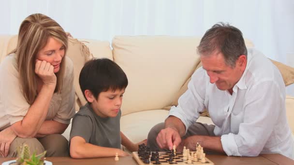 A boy playing chess with his grandfather — Stock Video