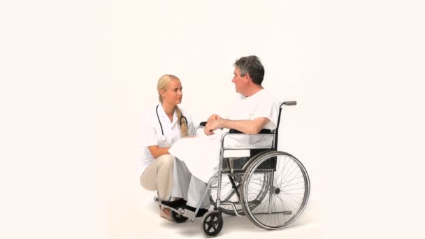 Man i en rullstol som talar till hans sjuksköterska — Stockvideo