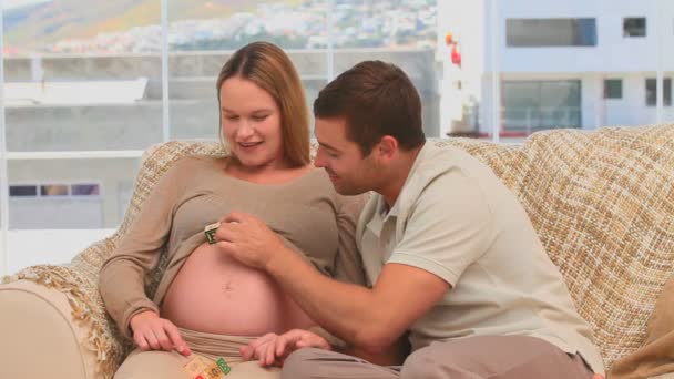 Άνθρωπος, βάζοντας το μωρό κύβους στην κοιλιά της γυναίκας του — Αρχείο Βίντεο