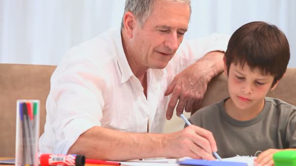 Een grootvader helpen zijn kleinzoon te doen zijn homeworks — Stockvideo