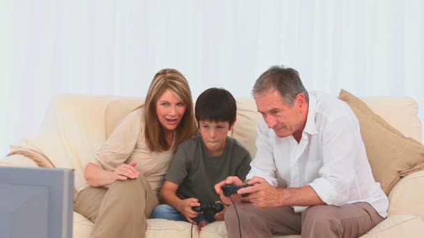 Мальчик, играющий в видеоигры со своим дедушкой — стоковое видео