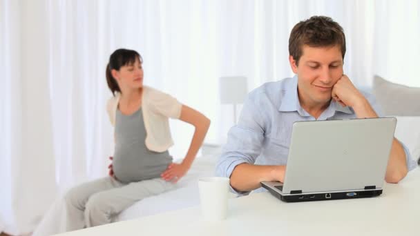 Donna incinta accarezzando la pancia mentre il suo fidanzato sta lavorando — Video Stock