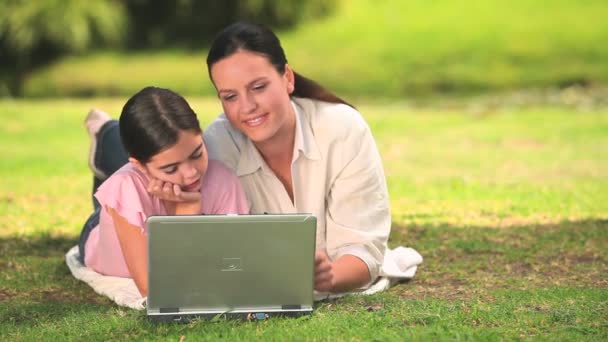Woman and daughter using a laptop outdoors — Wideo stockowe