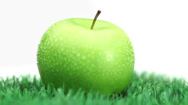 Manzana verde sobre hierba girando — Vídeos de Stock