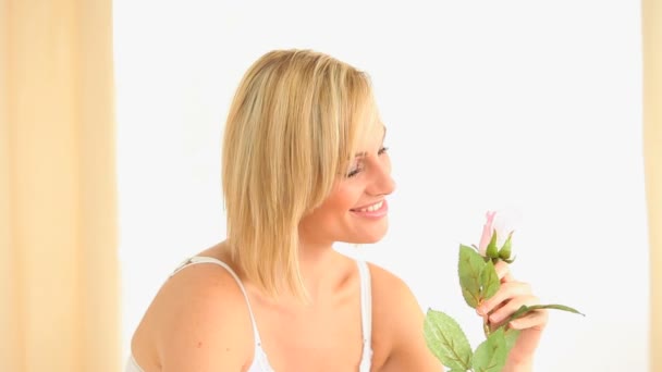 Mujer de pelo rubio oliendo una rosa — Vídeo de stock