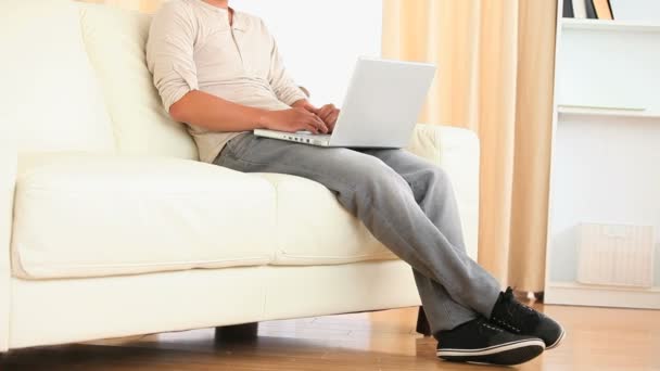 Man sitting on a sofa searching the web — Stockvideo