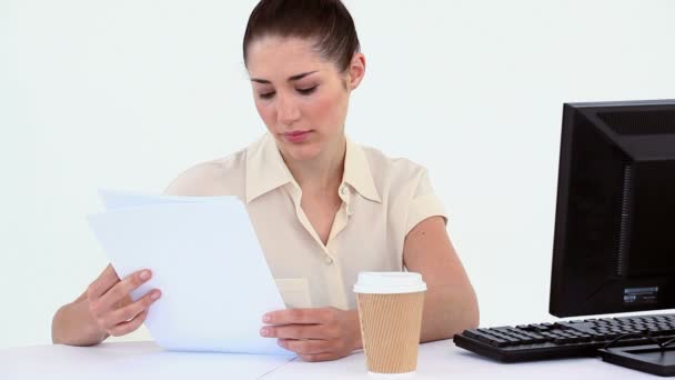 Kvinnlig arbetare läser en fil medan du sitter vid ett skrivbord — Stockvideo