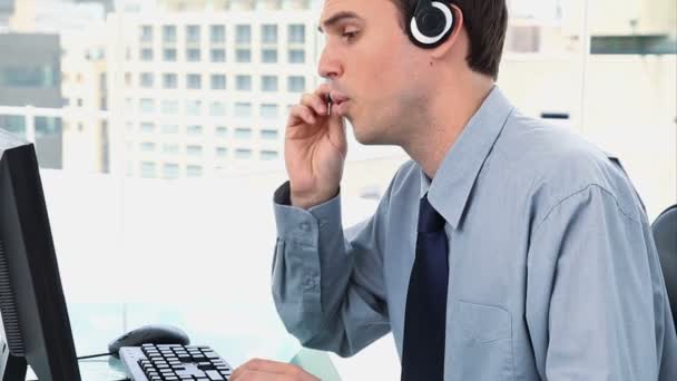 Businessman working with a computer and a headset — Stock Video