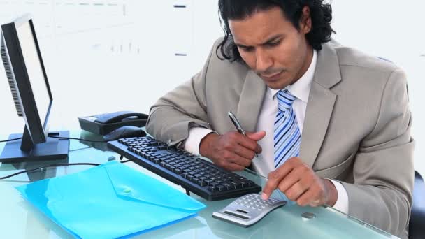 Businessman using a calculator while sitting a his desk — Stock Video