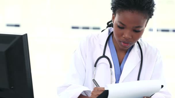 Doctora negra escribiendo en un portapapeles — Vídeo de stock