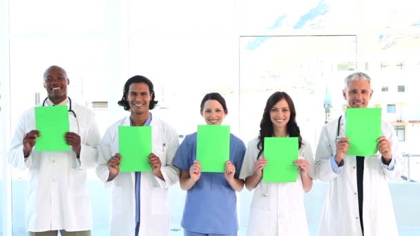 Equipe médica sorrindo mostrando papéis em branco — Vídeo de Stock