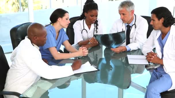 Médicos sorridentes sentados em uma mesa enquanto verificam um raio-x — Vídeo de Stock