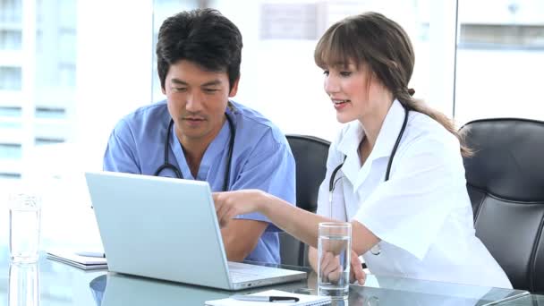 Doctor apuntando a la pantalla de un portátil con un colega — Vídeos de Stock