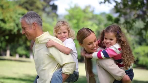 Parents turning with their children on their back — Stock Video