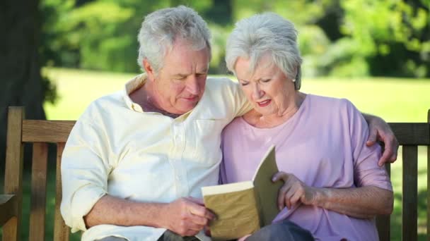 Pareja jubilada leyendo un libro juntos — Vídeos de Stock