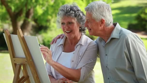 Lächelnder älterer Mann mit Blick auf seine Frau, die malt — Stockvideo