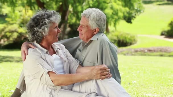 Happy mature couple talking while sitting on the grass — Stock Video