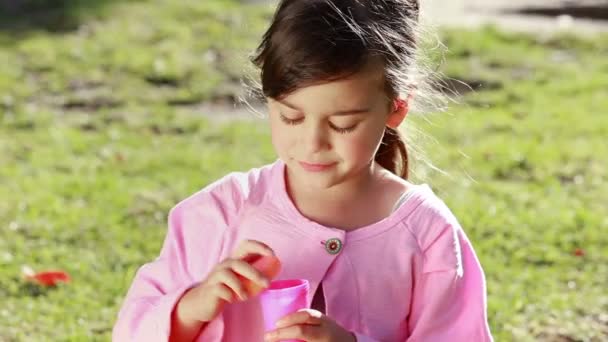 Happy little girl using a bubble wand — Stock Video