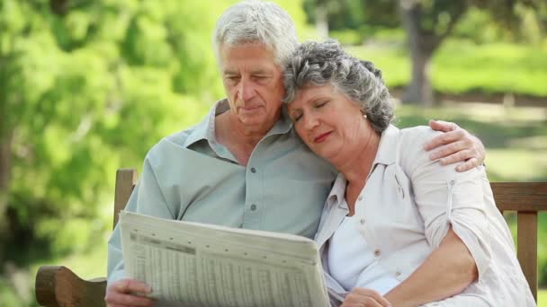 Mature man reading a newspaper while embracing his wife — Stock Video