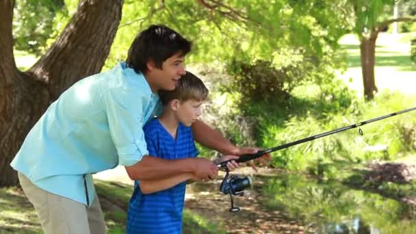 Feliz padre e hijo usando una caña de pescar — Vídeo de stock