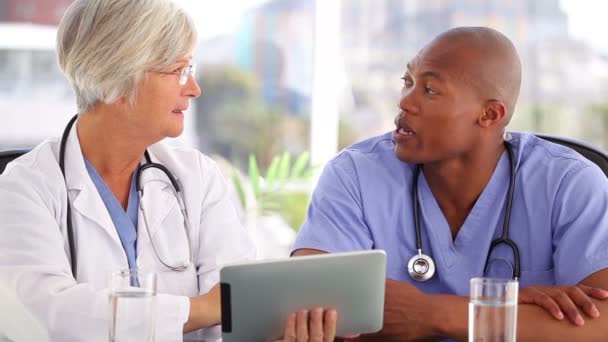 Médico maduro hablando con una enfermera delante de una pantalla táctil — Vídeo de stock