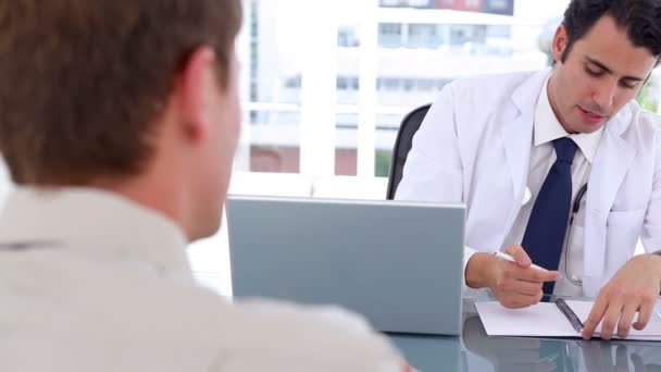 Серьезный врач разговаривает со своим пациентом, сидя — стоковое видео