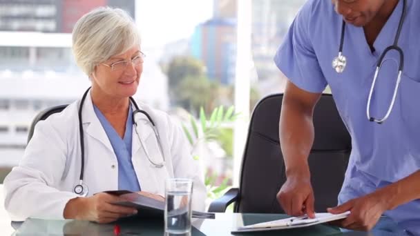 Usměvavá starší doktor zobrazuje dokumenty pro zdravotní sestry — Stock video
