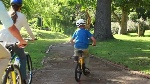 Boy riding a bike with his parents — Stockvideo