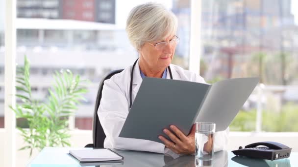 Smiling mature doctor looking at documents — Stock Video