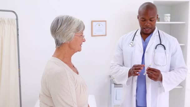 Доктор, стоящий перед пациентом со шприцем — стоковое видео