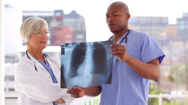 Серьёзный врач смотрит на рентген с медсестрой — стоковое видео